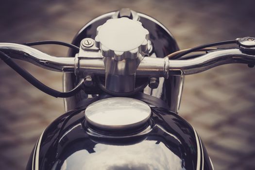 a vintage motorcycle handlebar in front of a cobblestone road