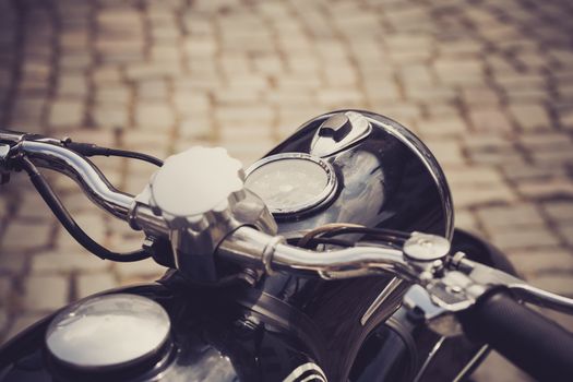 a vintage motorcycle with a cobblestone road in the background