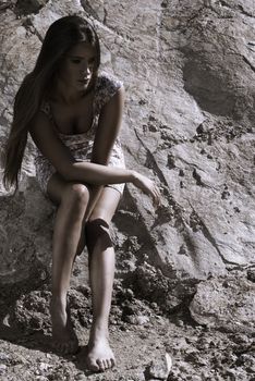 Lady in dress waiting against the rocks on a sunny day