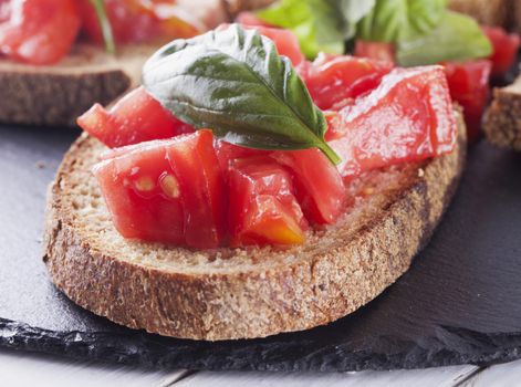 Bruschetta with tomato and basil over black stone