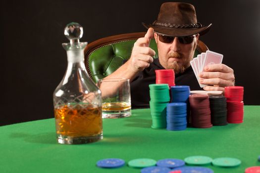 Photo of a man playing poker while wearing sunglasses and a hat.
