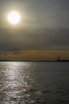 Sun setting over the hudson river with the statue of liberty in the background