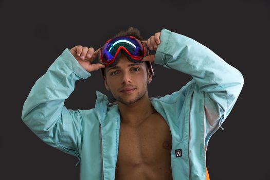 Friendly attractive skier or snowboarder with open jacket on naked muscular torso