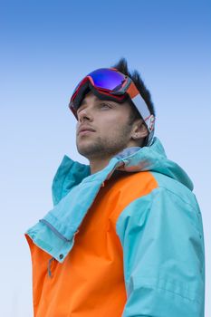 Friendly attractive skier or snowboarder against blue sky looking to a side off-camera