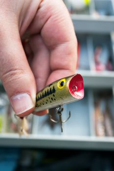A fishermen selects the lure from his tackle box that he is going to use. Shallow depth of field.