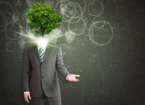Businessman stand with green tree and bright light instead his head. Eco concept