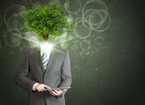 Businessman hold tablet pc. Green tree and bright light instead his head. Eco concept