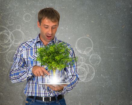 Man hold tablet pc with green tree and bright light. Eco concept