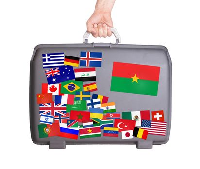 Used plastic suitcase with lots of small stickers, large sticker of Burkina Faso