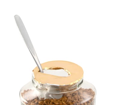 Metal teaspoon rests in a freshly opened jar of aromatic instant coffee granules - with copy space, isolated on a white background