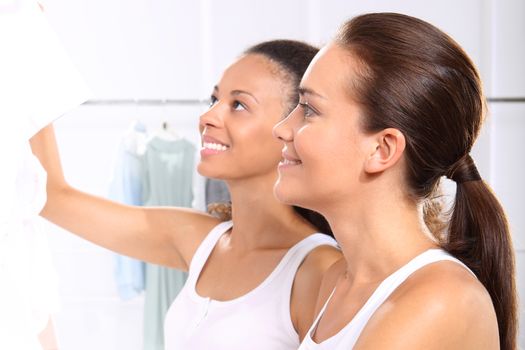 Two women shopping in boutique clothing, mulatto and Caucasian