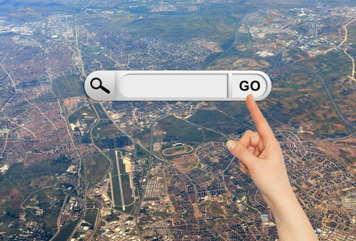 Human hand indicates the search bar in browser. Aerial view of the city on background
