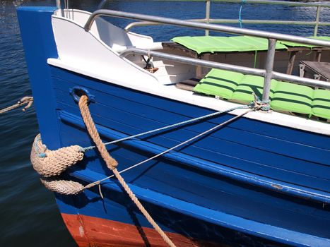 Prow of a small wooden tour boat docking in a marina 