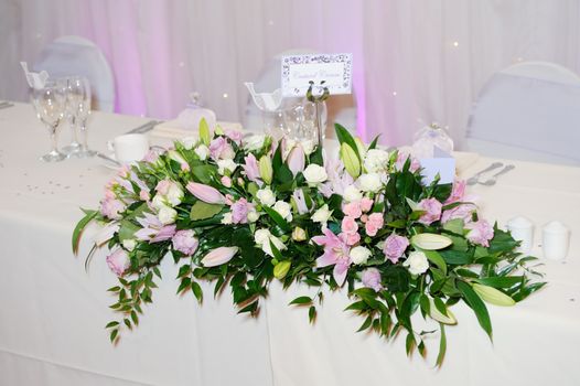 Flower arrangement with pink and purple roses decorates wedding reception
