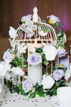 Wedding reception decoration is cage with flowers and butterfly