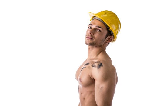 Profile view of muscular young construction worker shirtless wearing hardhat