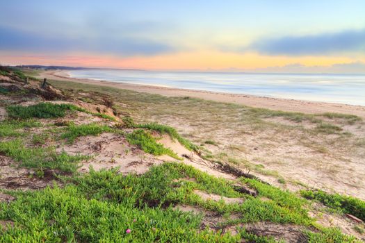 A combination of some light fog, low cloud at sunrise creates a mystical sky at the beach in the morning, the two ships on the horizon barely visible.   Central Coast NSW Australa.