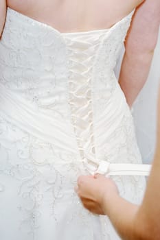 Brides white dress closeup being put on wedding day