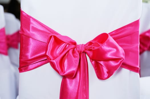 Closeup of red bow on chair cover at wedding reception