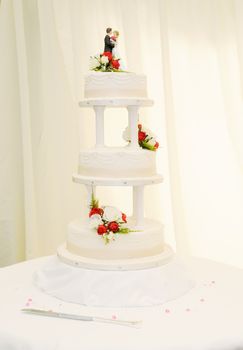 Wedding cake closeup at reception is white with bride and groom topper