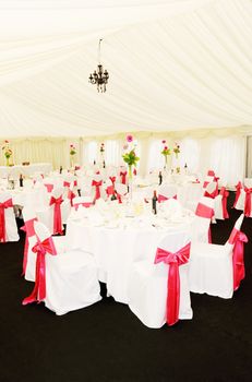 Wedding reception setting shows decoration of red ribbon and flowers