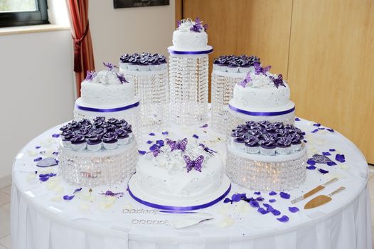 Huge wedding white and purple wedding cake at reception decorated with petals and butterflys