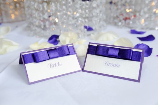 White and purple bride and groom place cards at wedding reception