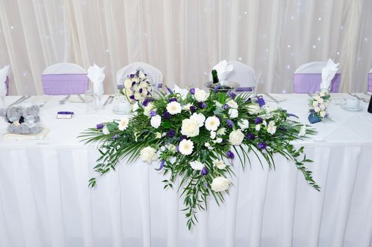 Table at wedding reception decorated with white and purple flowers