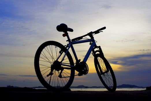 Silhouette of mountain bike with sunset sky and island, Chonburi, Thailand