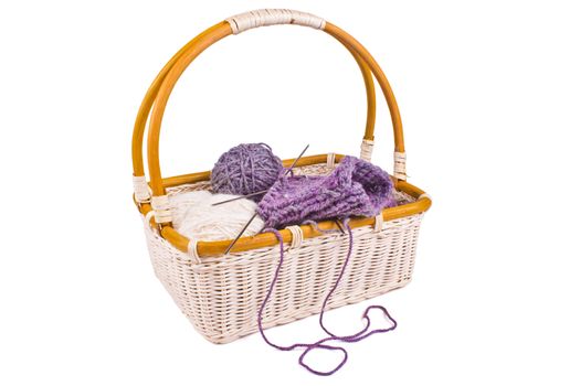 Basket with balls of wool yarn and knitting needles isolated on a white background