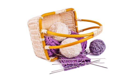 Basket with balls of wool yarn and knitting needles isolated on a white background