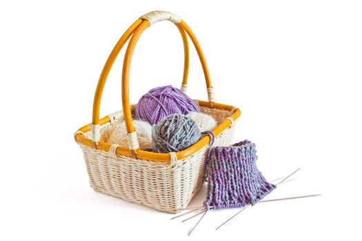 Basket with balls of wool yarn and knitting needles isolated on a white background