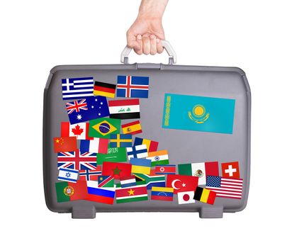 Used plastic suitcase with lots of small stickers, large sticker of Kazakhstan
