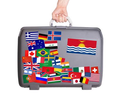 Used plastic suitcase with lots of small stickers, large sticker of Kiribati