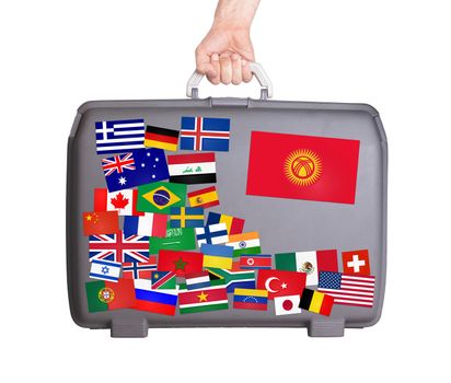 Used plastic suitcase with lots of small stickers, large sticker of Kyrgyzstan