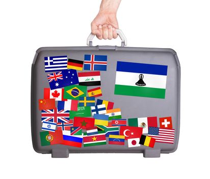 Used plastic suitcase with lots of small stickers, large sticker of Lesotho