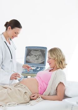 Female doctor performing ultrasound on pregnant woman in clinic