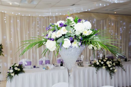 White and violet flowers decorate table at wedding reception