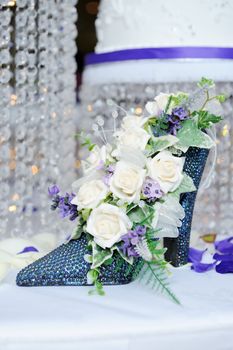 White rose in blue shoe decorate wedding reception with cake in background