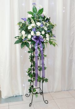 White and purple flower arrangement on stand at wedding reception