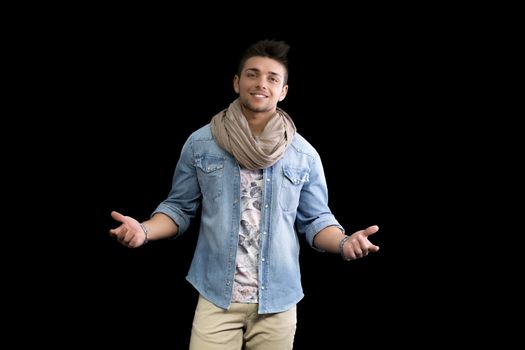 Handsome young man standing on black background with arms open, confident expression