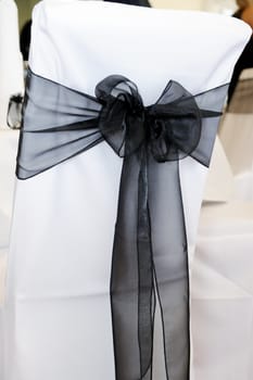 White and black chair cover with bow at wedding reception