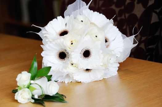 Brides bunch of white flowers and mothers corsage is white rose on wedding day