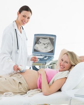 Portrait of female doctor using ultrasound scanner on pregnant woman in clinic