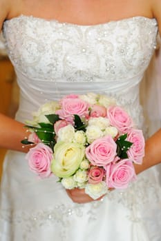 Close up of brides dress and bouquet at wedding