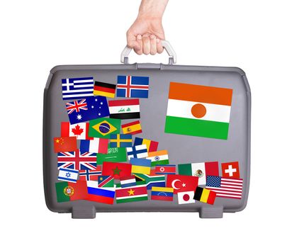 Used plastic suitcase with lots of small stickers, large sticker of Niger