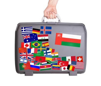 Used plastic suitcase with lots of small stickers, large sticker of Oman