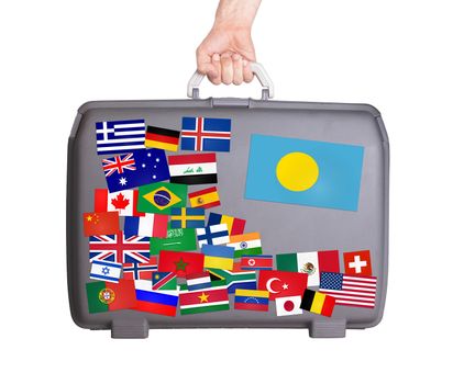 Used plastic suitcase with lots of small stickers, large sticker of Palau