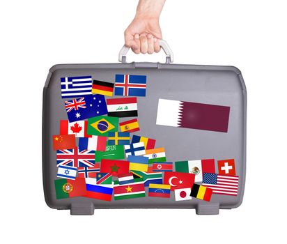 Used plastic suitcase with lots of small stickers, large sticker of Qatar