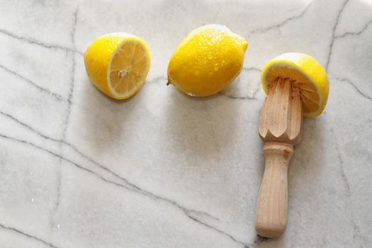 Fresh lemons and citrus reamer on marble counter top